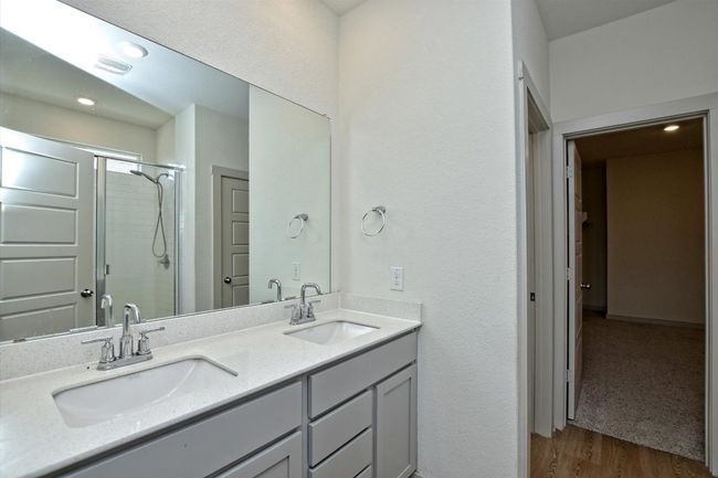 Full bath with double vanity, a shower with door, and wood finished floors | Image 23
