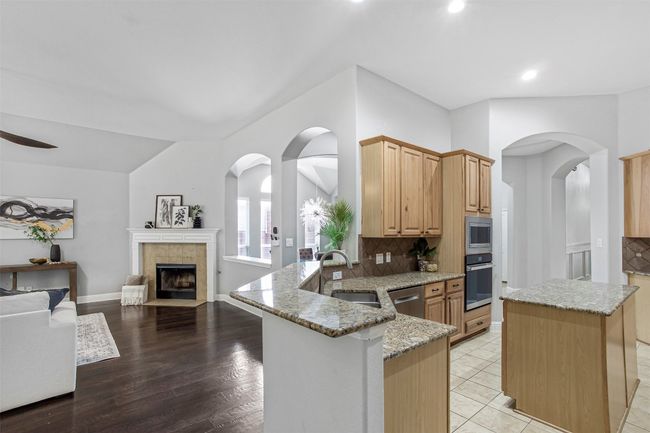 Kitchen with appliances with stainless steel finishes, a sink, light stone counters, tasteful backsplash, and recessed lighting | Image 13