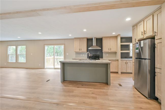 Kitchen featuring a sink, light wood-style floors, wall chimney exhaust hood, light countertops, and freestanding refrigerator | Image 7