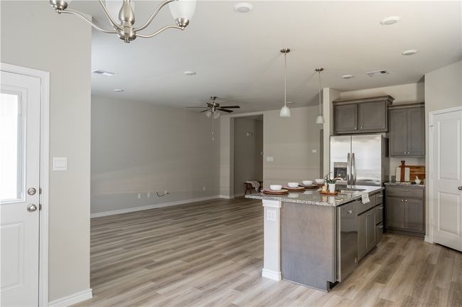 Kitchen with hanging light fixtures, light wood-style flooring, open floor plan, and appliances with stainless steel finishes | Image 5