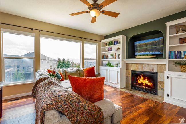 Living area with hardwood / wood-style flooring, a tiled fireplace, ceiling fan, and baseboards | Image 8