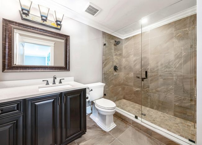 Bathroom with visible vents, ornamental molding, vanity, toilet, and a stall shower | Image 15