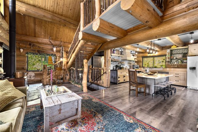 Living room with log walls, wood finished floors, wooden ceiling with exposed beams, and a wood stove | Image 13