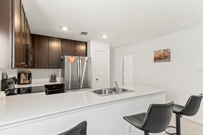 Kitchen featuring freestanding refrigerator, electric stove, dark brown cabinetry, a kitchen bar, and recessed lighting | Image 15