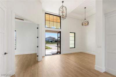 Entrance foyer featuring light hardwood / wood-style flooring, a high ceiling, and a chandelier | Image 2