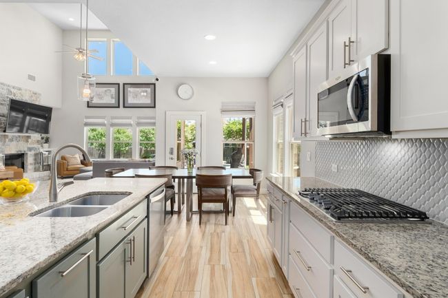 Kitchen featuring a wealth of natural light, tasteful backsplash, stainless steel appliances, gas cooktop and microwave vented to the outside. | Image 7