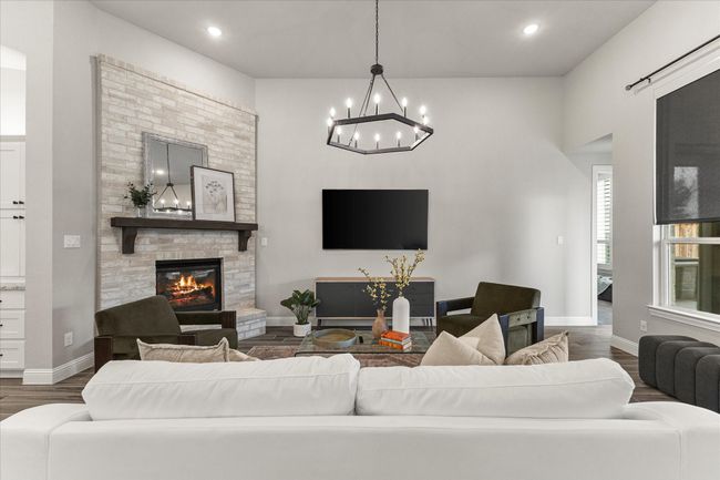 Living area featuring dark wood-type flooring, a chandelier, a fireplace, and recessed lighting | Image 13