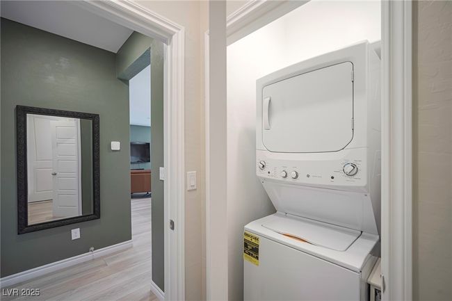 Laundry room featuring stacked washer and dryer, baseboards, laundry area, and light wood-style floors | Image 9