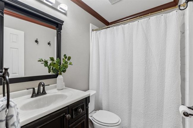 Bathroom with vanity, crown molding, toilet, and a textured wall | Image 9