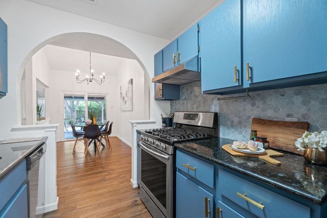 Kitchen with stainless steel appliances, blue cabinetry, under cabinet range hood, decorative marble hex tiled backsplash | Image 7