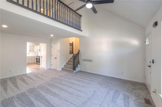 Unfurnished living room featuring light carpet, high vaulted ceiling, stairs, ceiling fan, and recessed lighting | Image 4
