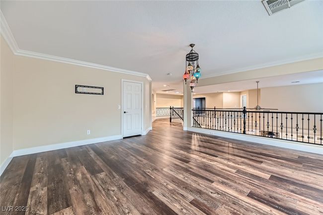Empty room with crown molding, wood finished floors, and a chandelier | Image 34