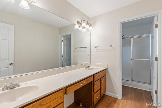 Full bathroom featuring wood finished floors, double vanity, a stall shower, and baseboards | Image 15