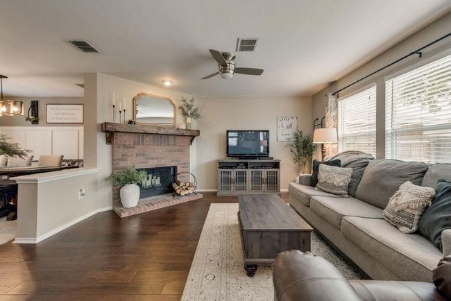 Living area featuring a ceiling fan, hardwood / wood-style floors, and a fireplace | Image 6
