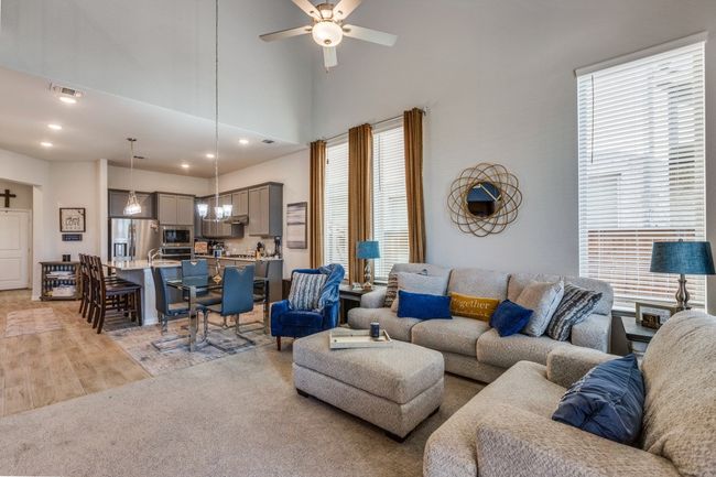 Living area featuring plenty of natural light, light wood-style flooring, a ceiling fan, recessed lighting, and a high ceiling | Image 8