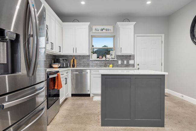 Kitchen with sink, white cabinetry, tasteful backsplash, a kitchen island, and stainless steel appliances | Image 12
