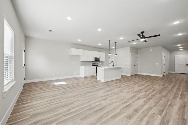Unfurnished living room with a ceiling fan, a sink, light wood-style floors, and a healthy amount of sunlight | Image 9