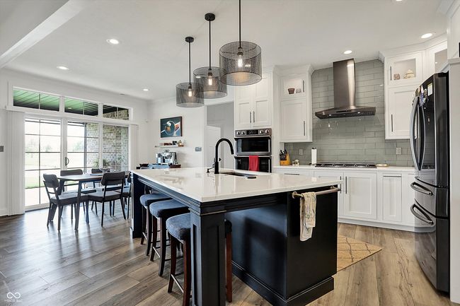 kitchen featuring wall chimney range hood, tasteful backsplash, a sink, stainless steel appliances, and light countertops | Image 15