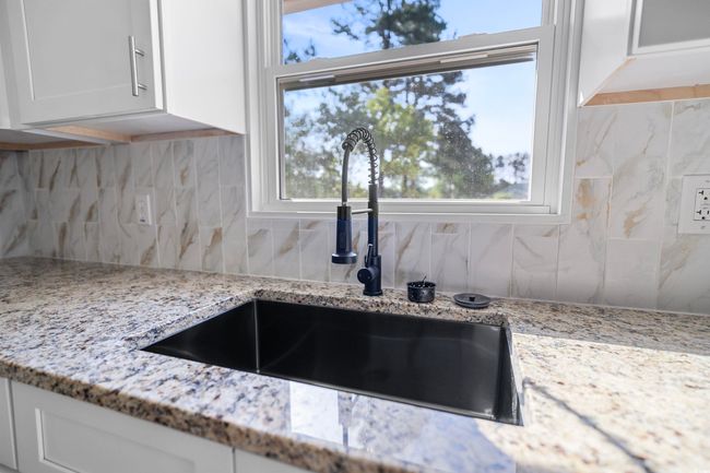 Kitchen view of decorative backsplash, white cabinetry, and light stone counters | Image 31