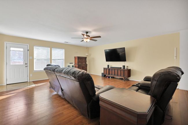 Living area with a ceiling fan and wood finished floors | Image 4