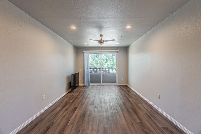 Unfurnished room with dark wood finished floors, ceiling fan, a textured ceiling, a textured wall, and recessed lighting | Image 4