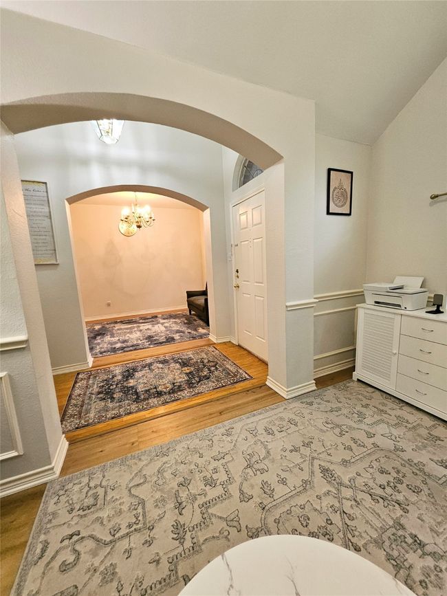 Entryway with arched walkways, wood finished floors, a chandelier, and lofted ceiling | Image 18