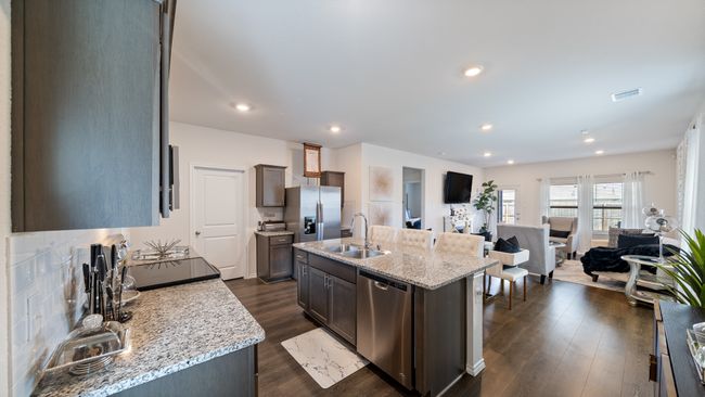 Kitchen with stainless steel appliances, open floor plan, dark wood-style flooring, light stone countertops, and recessed lighting | Image 4