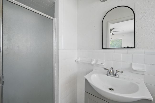 Bathroom featuring vanity, a shower stall, tile walls, wainscoting, and a ceiling fan | Image 5
