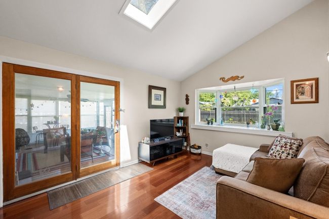 Living area featuring a skylight, high vaulted ceiling, wood finished floors, and baseboards | Image 7