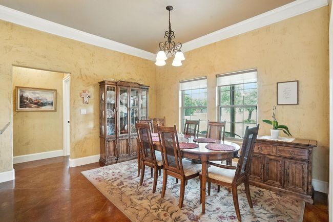 Dining space with ornamental molding, a chandelier, and concrete flooring | Image 13