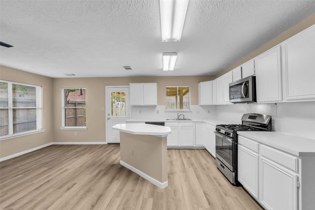 Delightful and bright kitchen with tons of cabinets for storage, island and SS appliances. | Image 9