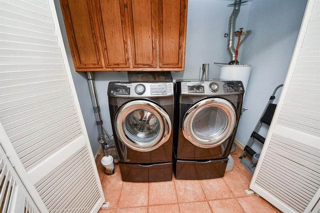 This indoor utility closet features a front loading washing and dryer that convey with the home. | Image 19