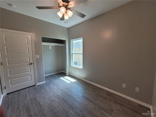 Unfurnished bedroom with dark wood finished floors, baseboards, a ceiling fan, and a closet | Image 6