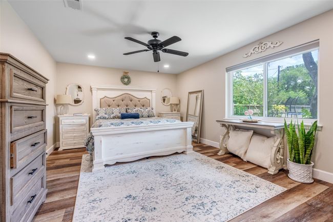 Retreat to the serene primary bedroom, featuring a large window with privacy blinds, elegant vinyl plank flooring, and a stylish ceiling fan for ultimate comfort and relaxation! | Image 9