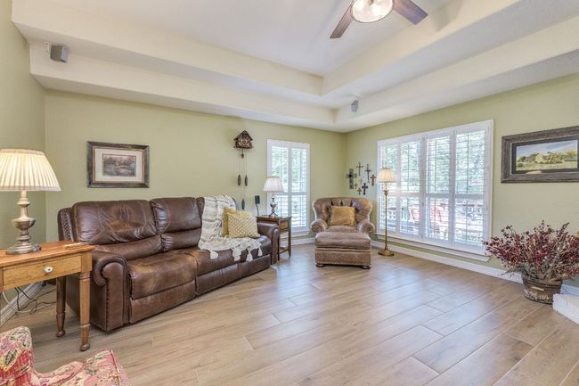 Living area featuring a raised ceiling, ceiling fan, and light wood-style tile floors | Image 26
