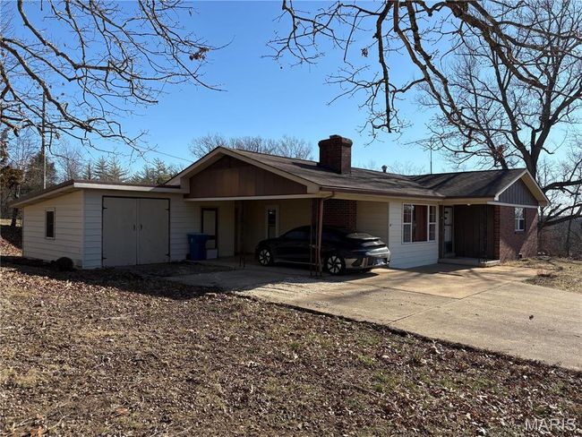 View of front of home featuring a carport, concrete driveway, brick siding, and a chimney | Image 4