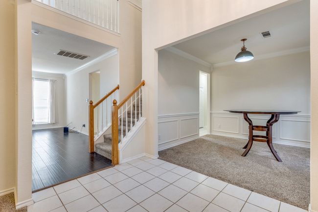Tiled entryway featuring carpet flooring, a decorative wall, crown molding, and visible vents | Image 5