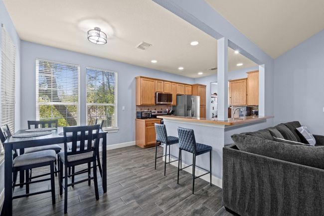 Kitchen with dark wood-type flooring, a breakfast bar, appliances with stainless steel finishes, and open floor plan | Image 11