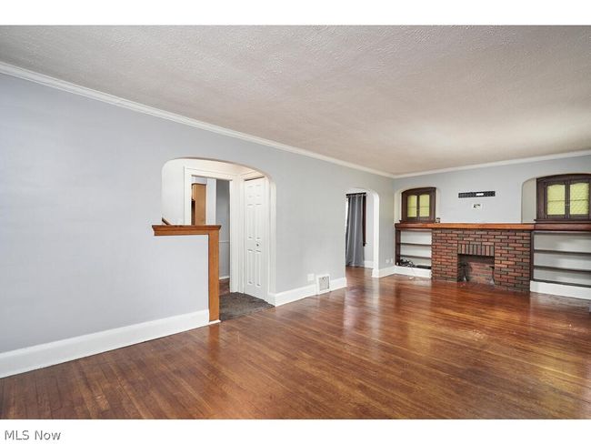 Unfurnished living room featuring a textured ceiling, a fireplace, hardwood / wood-style flooring, and crown molding | Image 4