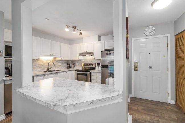 Kitchen with under cabinet range hood, white cabinets, appliances with stainless steel finishes, and a sink | Image 14