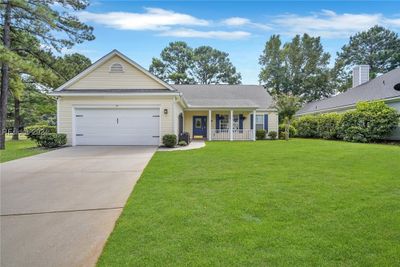 View of front of house featuring covered porch, a front yard, and a garage | Image 2