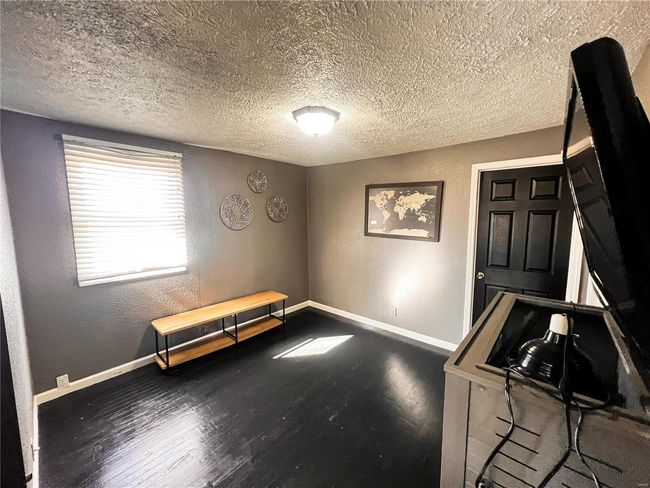 Misc room featuring a textured wall, a textured ceiling, baseboards, and wood finished floors | Image 12