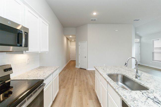 Kitchen with appliances with stainless steel finishes, backsplash, a sink, and white cabinetry | Image 17