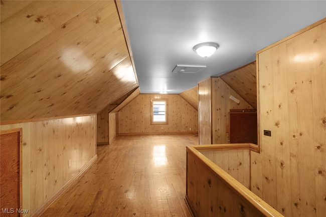 primary bedroom with lofted ceiling, wooden walls, and wood finished floors | Image 17