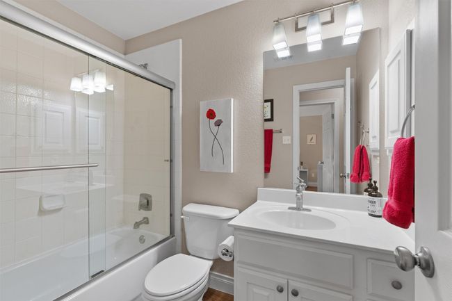 Bathroom with vanity, toilet, combined bath / shower with glass door, and a textured wall | Image 25
