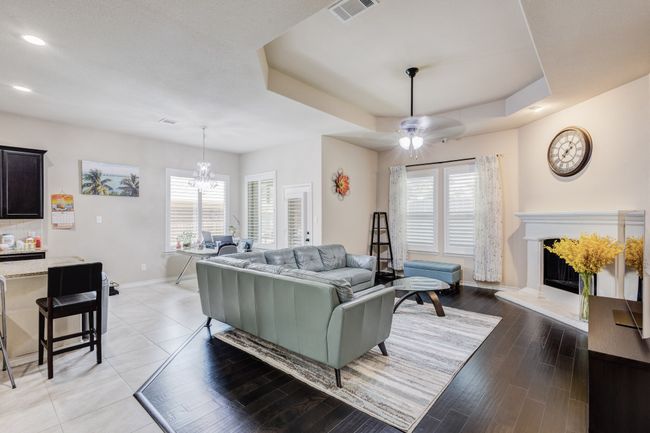 Living room with baseboards, a fireplace with raised hearth, a chandelier, recessed lighting, and a raised ceiling | Image 17