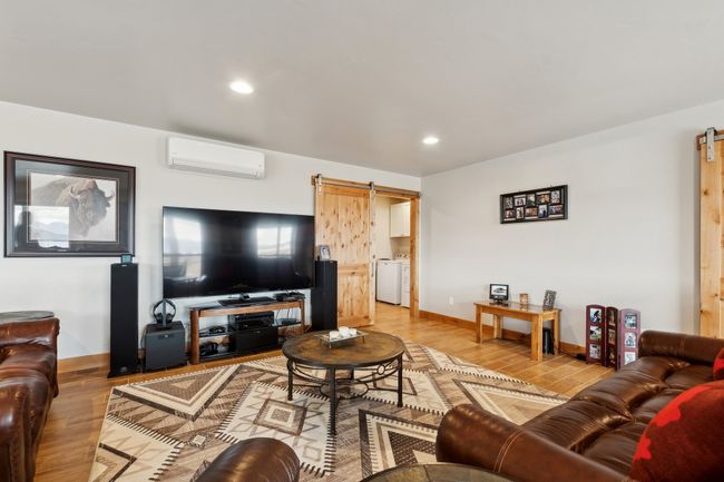 Living room featuring washer / dryer, an AC wall unit, a barn door, and wood-type flooring | Image 32