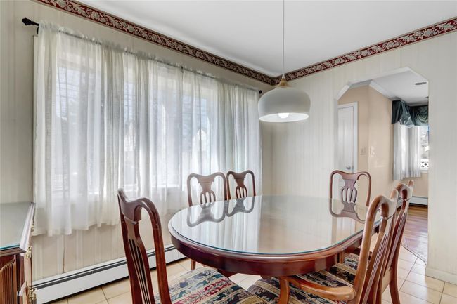 Dining space with a wealth of natural light, a baseboard radiator, arched walkways, and light tile patterned floors | Image 7