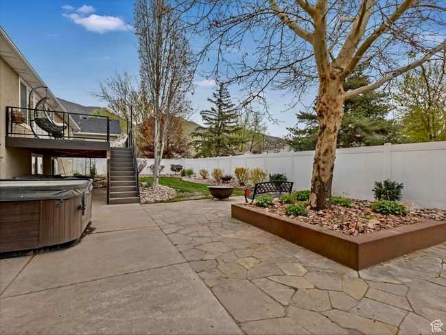 View of new natural stone patio with custom welded bench with a hot tub and fully fenced backyard | Image 33