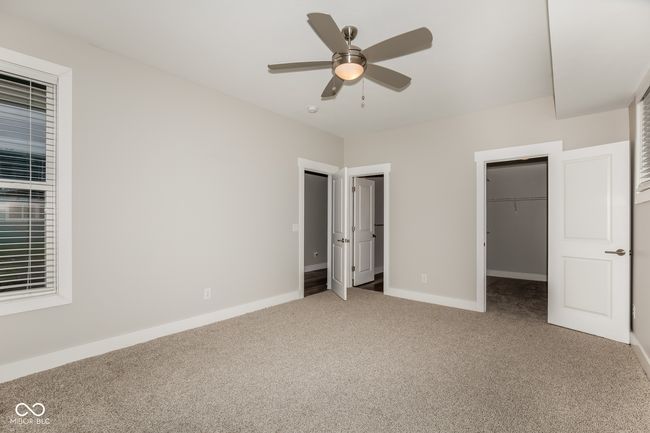 unfurnished bedroom with baseboards, a ceiling fan, carpet flooring, and a walk in closet | Image 8